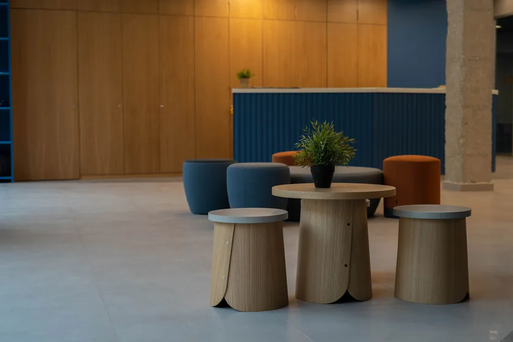Recepción del nuevo hall de la residencia, con mostrador azul, madera y taburetes de colores