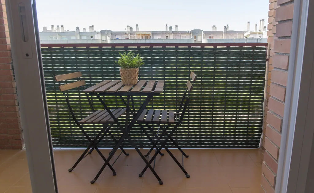 Terraza de un piso-residencia con mesa y sillas plegables