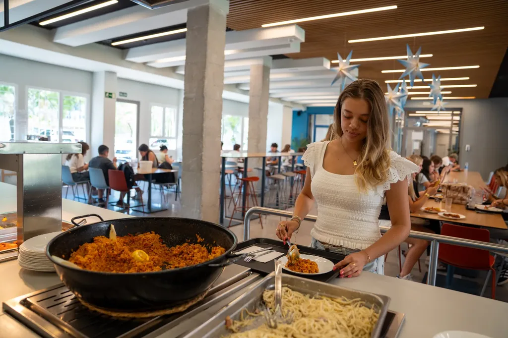 Estudiante sirviéndose comida casera en el comedor de la residencia
