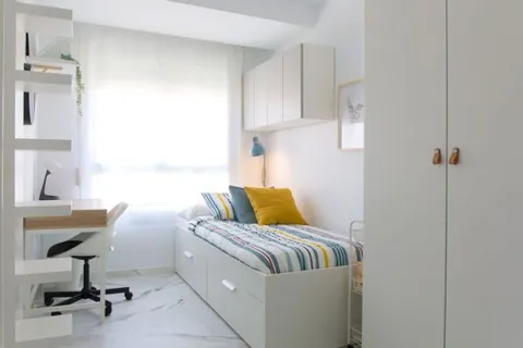 Habitación individual con cama, escritorio y armario