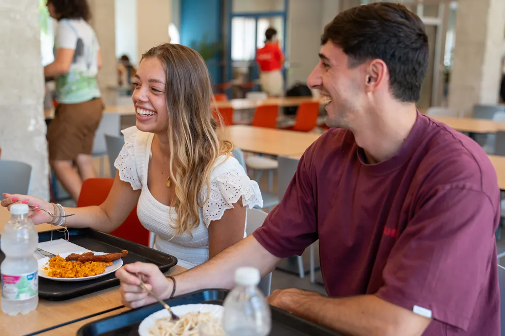 Dos residentes comiendo y riendo en el comedor de la residencia