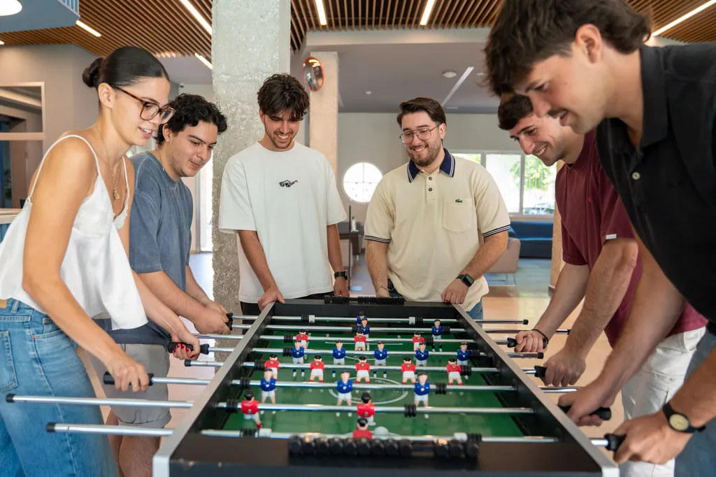 Grupo de residentes jugando una partida de futbolín en el hall de la residencia