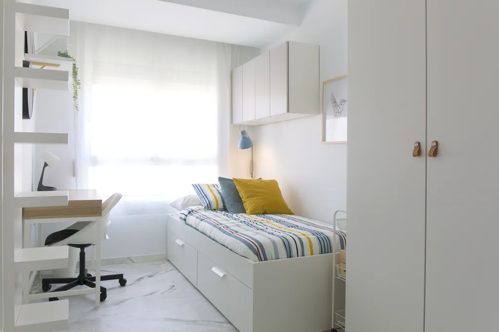 Habitación exterior con cama, escritorio y luz natural